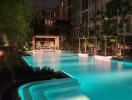 Elegant outdoor swimming pool with illuminated water and surrounding greenery at nighttime