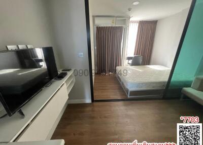 Spacious bedroom with integrated living area featuring a large bed, television, and balcony access
