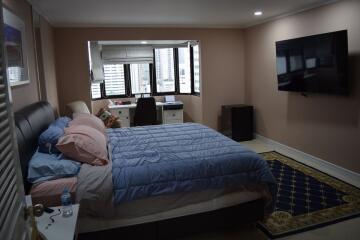 Modern bedroom with a large bed, wall-mounted TV, and window