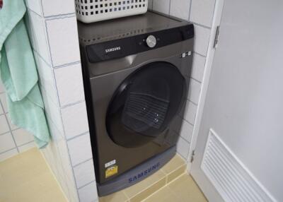 Samsung washing machine in a small white tiled laundry room space