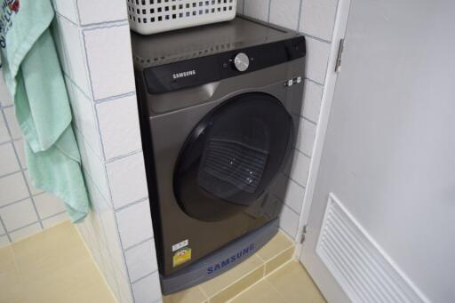 Samsung washing machine in a small white tiled laundry room space