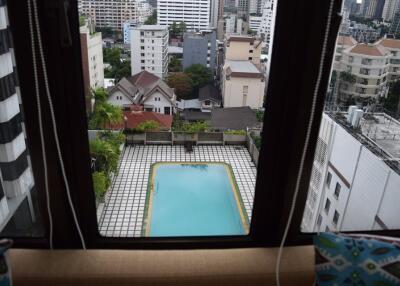 View of swimming pool and cityscape from apartment window