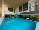 Modern indoor pool with large windows and balcony in a luxury home