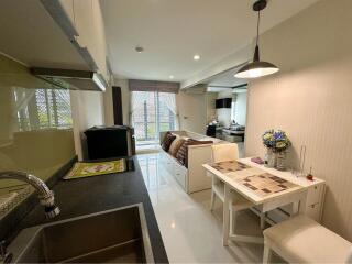 Modern studio apartment interior with kitchen, dining area, and bedroom in the background