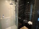 Modern bathroom with marble walls and glass shower enclosure