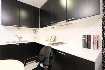 Modern compact kitchen with black cabinetry and white countertops