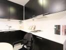 Modern compact kitchen with black cabinetry and white countertops