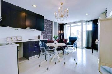 Elegant modern kitchen with dining area, featuring black cabinetry and a chic glass dining table