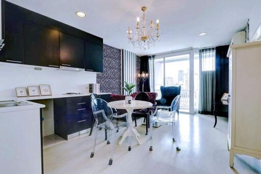 Elegant modern kitchen with dining area, featuring black cabinetry and a chic glass dining table