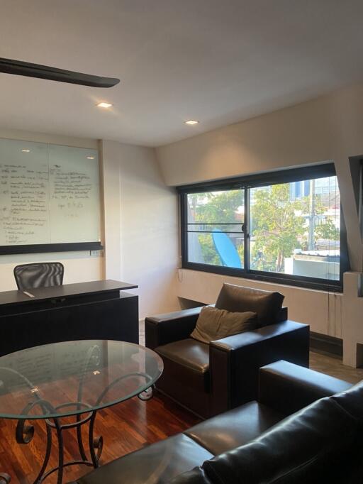 Modern office room with glass table, leather sofa, and large windows