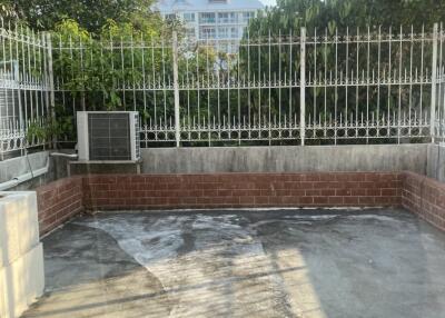 View of a spacious outdoor balcony with a brick and concrete floor overlooking a surrounding area through white metal fences