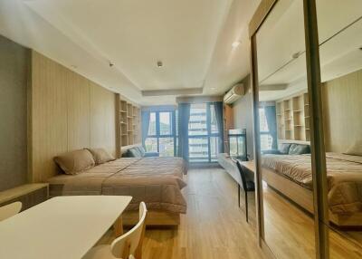 Modern bedroom with a large bed, mirrored wardrobe, and wooden wall panels