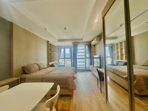 Modern bedroom with a large bed, mirrored wardrobe, and wooden wall panels