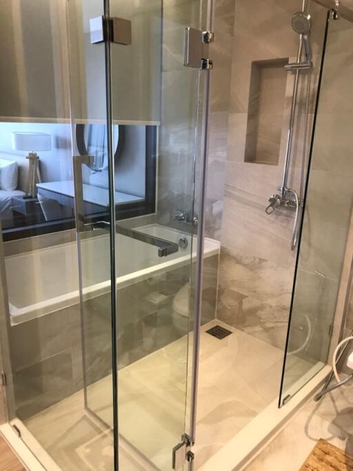 Modern bathroom with clear glass shower enclosure and visible bathtub