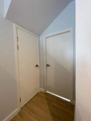 Well-lit hallway with wooden flooring and white doors