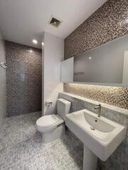 Modern bathroom with patterned tile walls and white fixtures