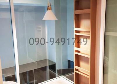 Modern interior of an unfinished apartment showing a glass partition and wooden shelving