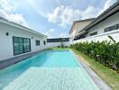 Luxurious outdoor pool area with adjacent modern homes under clear blue sky