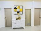 Elegant hallway interior with modern artistic wall decor and a white storage cabinet