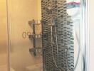 Modern shower corner with metallic fixtures in a tiled bathroom