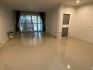 Spacious and bright unfurnished living room with large windows and glossy tiled flooring