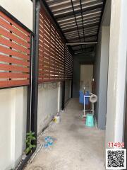 Narrow outdoor passage between building walls featuring a slatted wooden fence