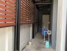 Narrow outdoor passage between building walls featuring a slatted wooden fence