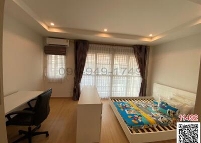 Spacious and well-lit bedroom with a large window, comfortable bed, and a dedicated workspace