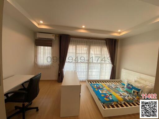 Spacious and well-lit bedroom with a large window, comfortable bed, and a dedicated workspace