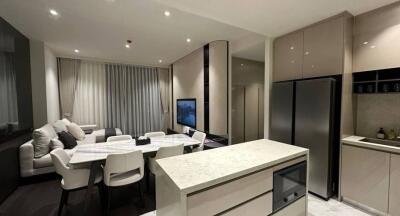 Modern kitchen integrated with a small dining area featuring sleek design and neutral tones