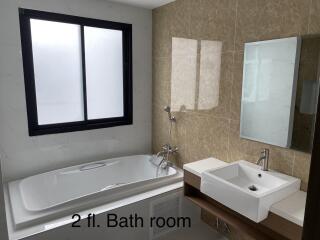 Spacious modern bathroom with large bathtub, window, and sink