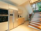 Modern kitchen with integrated appliances and wooden staircase in a contemporary home