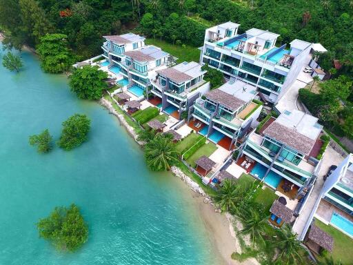 Aerial view of a modern waterfront residential building complex surrounded by lush greenery