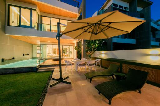 Luxurious modern house exterior with pool and lounging area during twilight