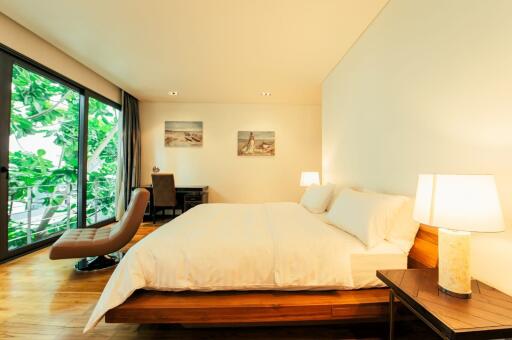 Spacious bedroom with large bed and view of the nature through glass doors