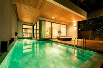 Luxurious home swimming pool adjacent to a modern bedroom at night