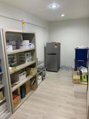 Well-organized storage room with shelving units and modern refrigerator