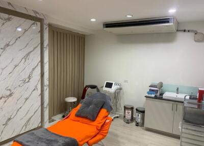 Modern medical treatment room with orange treatment bed and advanced equipment