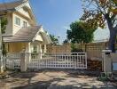 Front view of a suburban house with white fence and clear blue sky