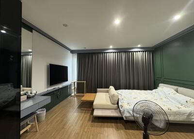 Modern bedroom with combined living area featuring stylish decor and ample lighting
