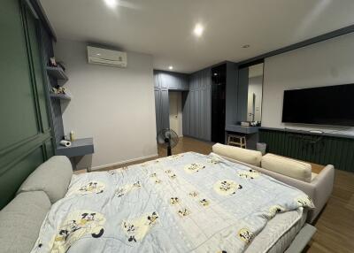 Spacious modern bedroom with large bed, flat-screen TV, and air conditioning unit