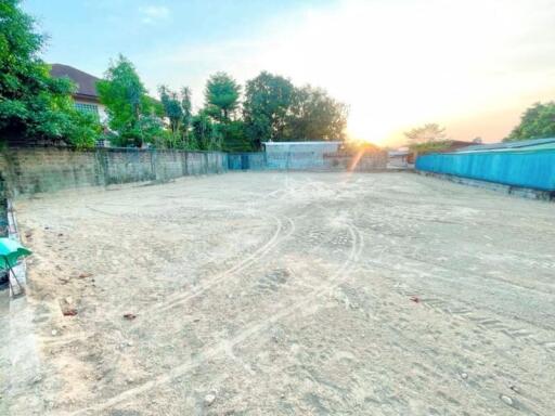 Spacious empty land plot with surrounding walls under a sunset