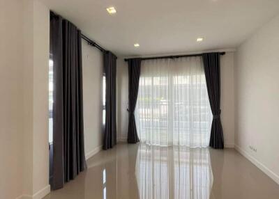 Spacious and well-lit living room with glossy tiled flooring and elegant curtains