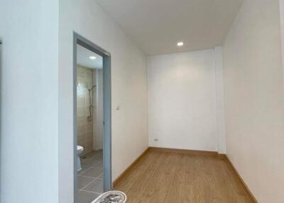 Spacious, well-lit hallway leading to a bathroom with wooden flooring