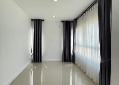 Bright and modern hallway with glossy floor tiles and large windows draped with black curtains