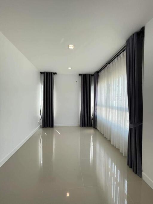 Bright and modern hallway with glossy floor tiles and large windows draped with black curtains