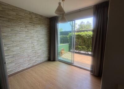 Spacious living room with stone wall and sliding door leading to a balcony