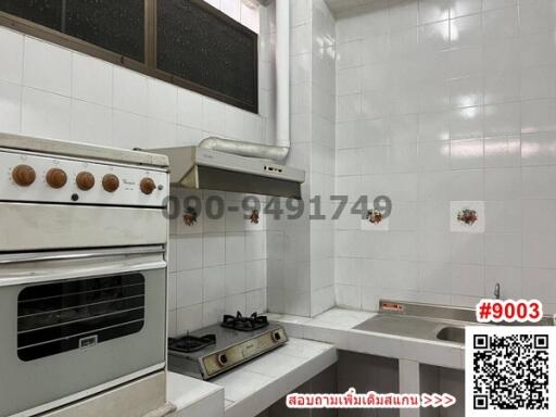 Compact kitchen with white tiles and vintage appliances