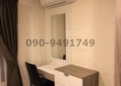 Compact bedroom with desk, air conditioning, and white brick wall