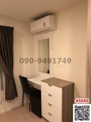 Compact bedroom with desk, air conditioning, and white brick wall